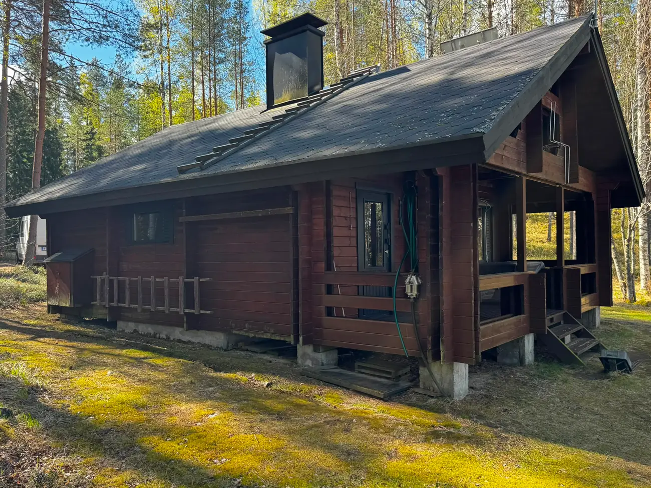 Hirsimökin julkisivu ennen maalausta, haalistunut ja sään harmaannuttama puupinta